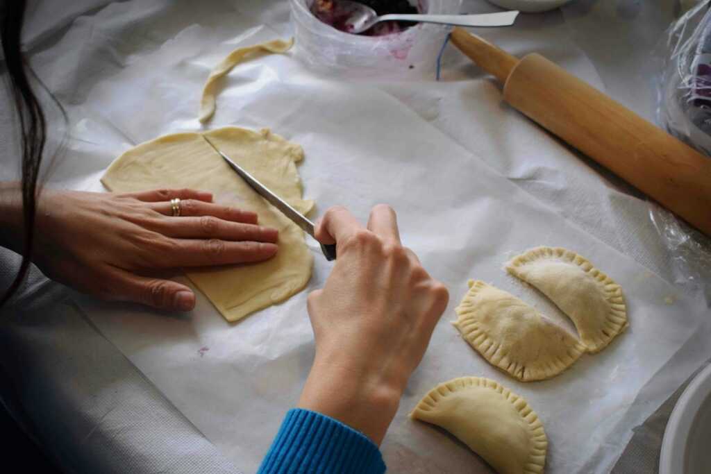 Manos formando y cerrando empanadillas antes de hornearlas