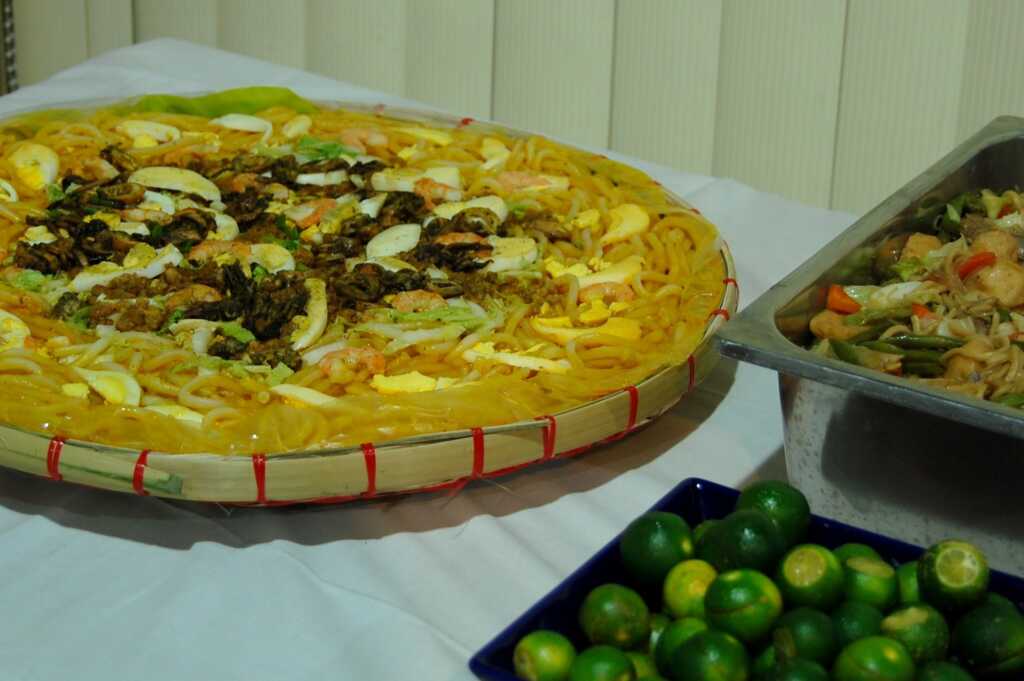 Pancit Malabon filipino con fideos gruesos, marisco, huevo y calamansi