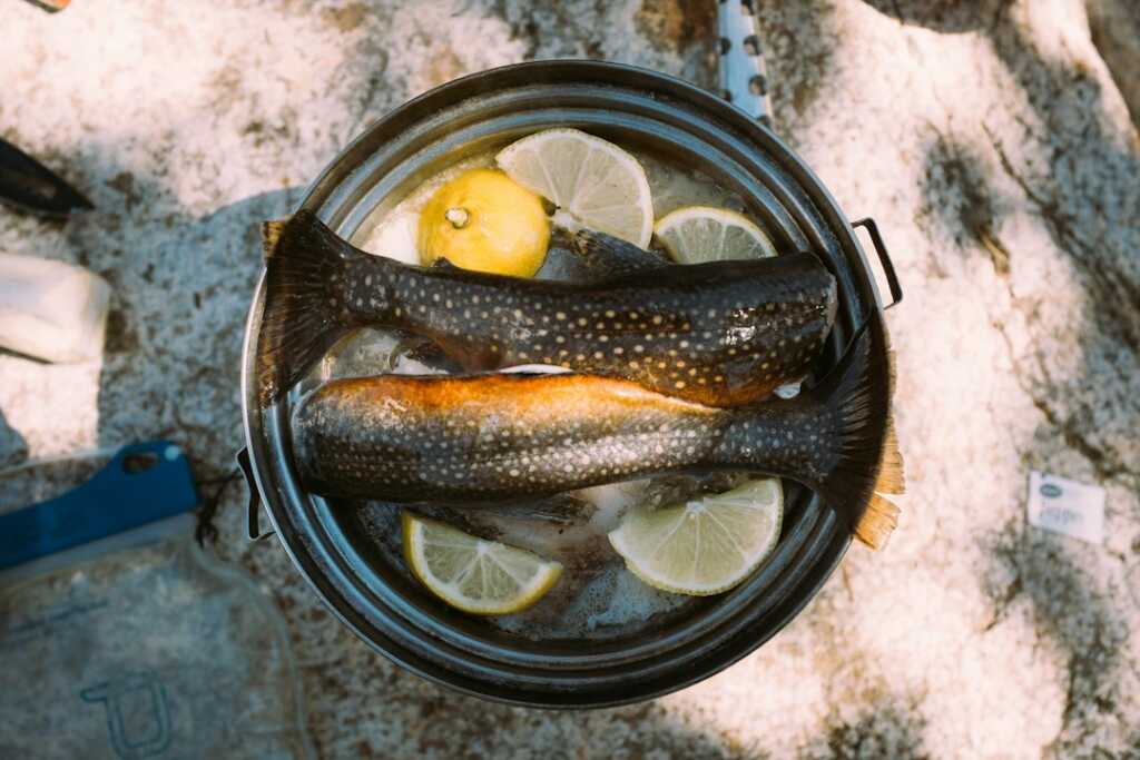 Pescado entero cocinándose en sartén para una receta de trucha a la navarra