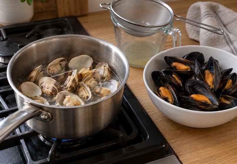 Caldereta de marisco con patatas 4 Almejas abiertas en un cazo y mejillones cocidos reservados en un cuenco
