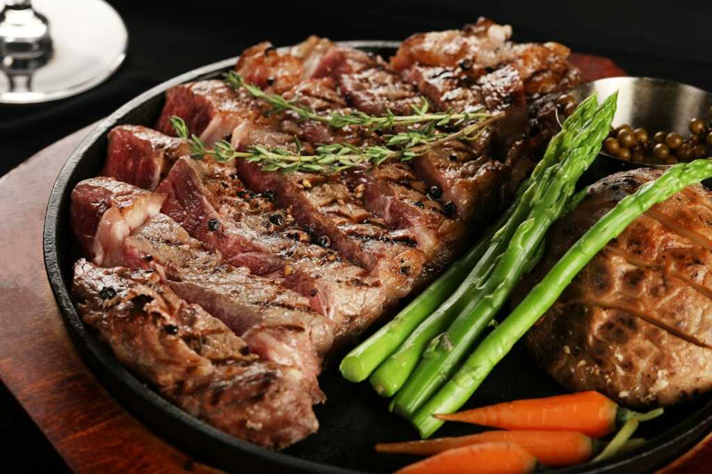 Chuletón de vacuno cocinado y dorado sobre una bandeja, listo para servir